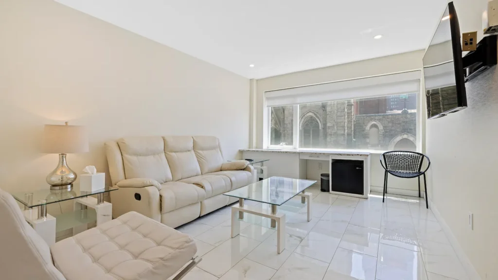 A bright and modern living room with a sofa, coffee table, chair, and TV.